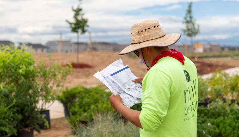 Un miembro del equipo de Mill Brothers revisa los planos de paisajismo en una obra de Denver
